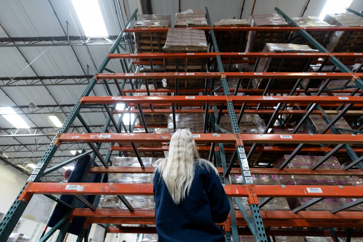 Kvinnelig DSV medarbeider registrerer varer ved en lagerreol på lager